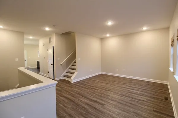 a view of an empty room with wooden floor and stairs