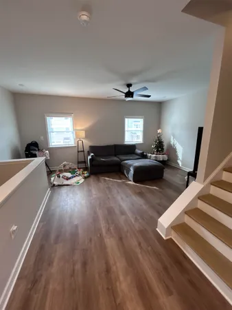 a view of a livingroom with furniture a ceiling fan and wooden floor