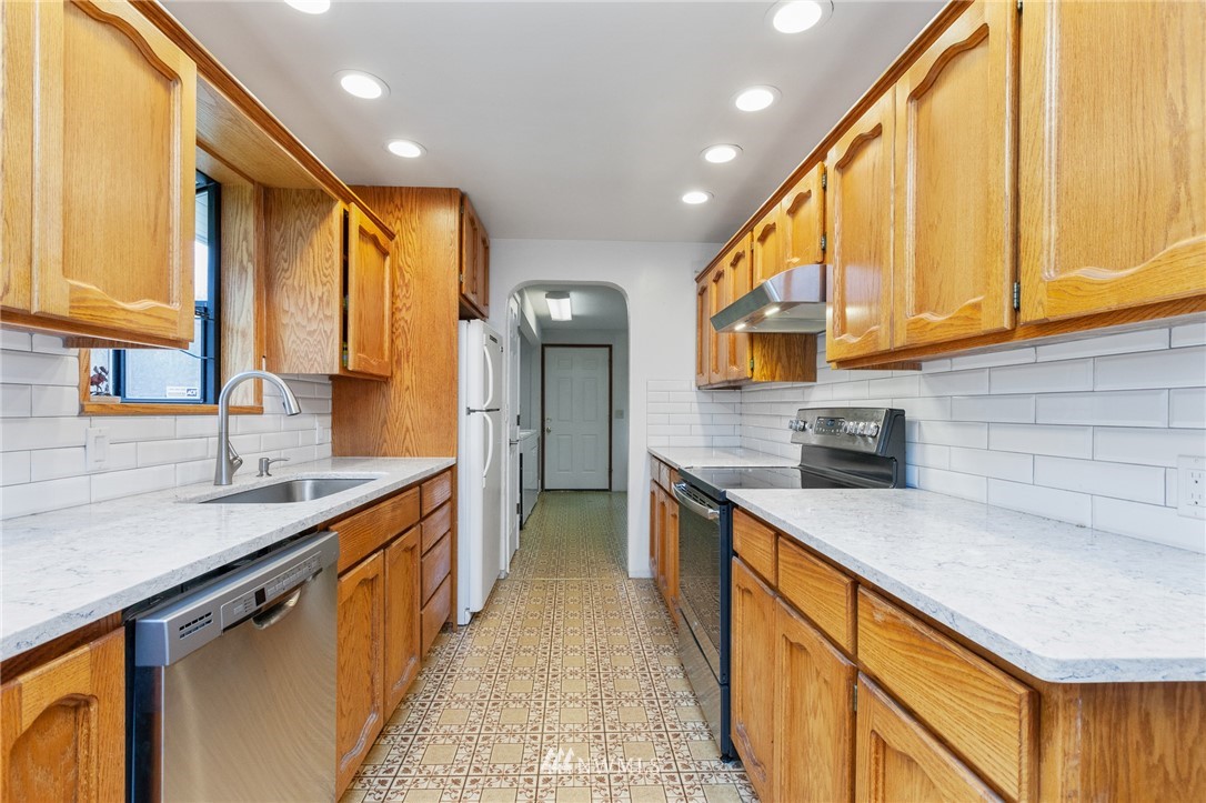 15408 Southeast Jones Road Renton, WA 98058 - Photo 11 of 40 a kitchen with stainless steel appliances granite countertop a sink a stove and a refrigerator