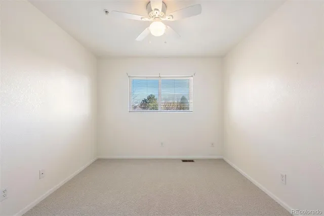 an empty room with a fan & a window