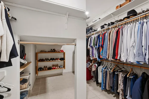 a view of walk in closet with clothes and shoes