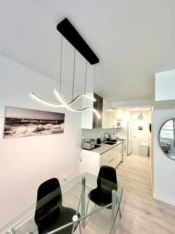 a kitchen with stainless steel appliances a stove a refrigerator a sink a dining table and chairs with wooden floor