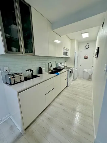 a kitchen with stainless steel appliances a sink a stove a refrigerator a microwave and cabinets