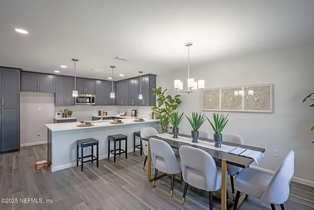a view of a dining room and livingroom with furniture wooden floor a chandelier