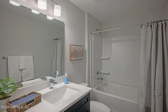 a bathroom with a sink vanity granite tub shower and a mirror