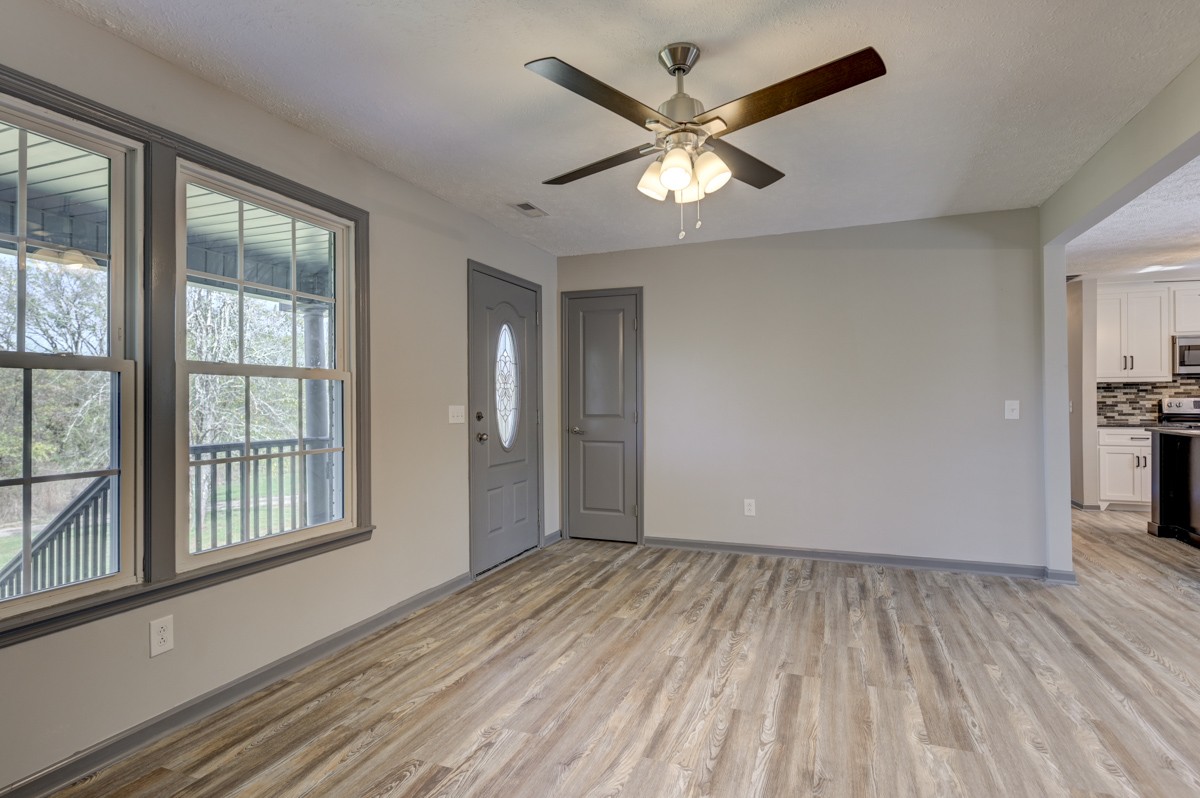 300 Garrison Branch Road Cottontown, TN 37048 - Photo 15 of 50 an empty room with wooden floor chandelier fan and windows