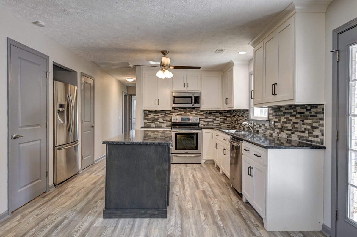 300 Garrison Branch Road Cottontown, TN 37048 - Photo 17 of 50 a kitchen with granite countertop a refrigerator a sink dishwasher a stove and white cabinets with wooden floor