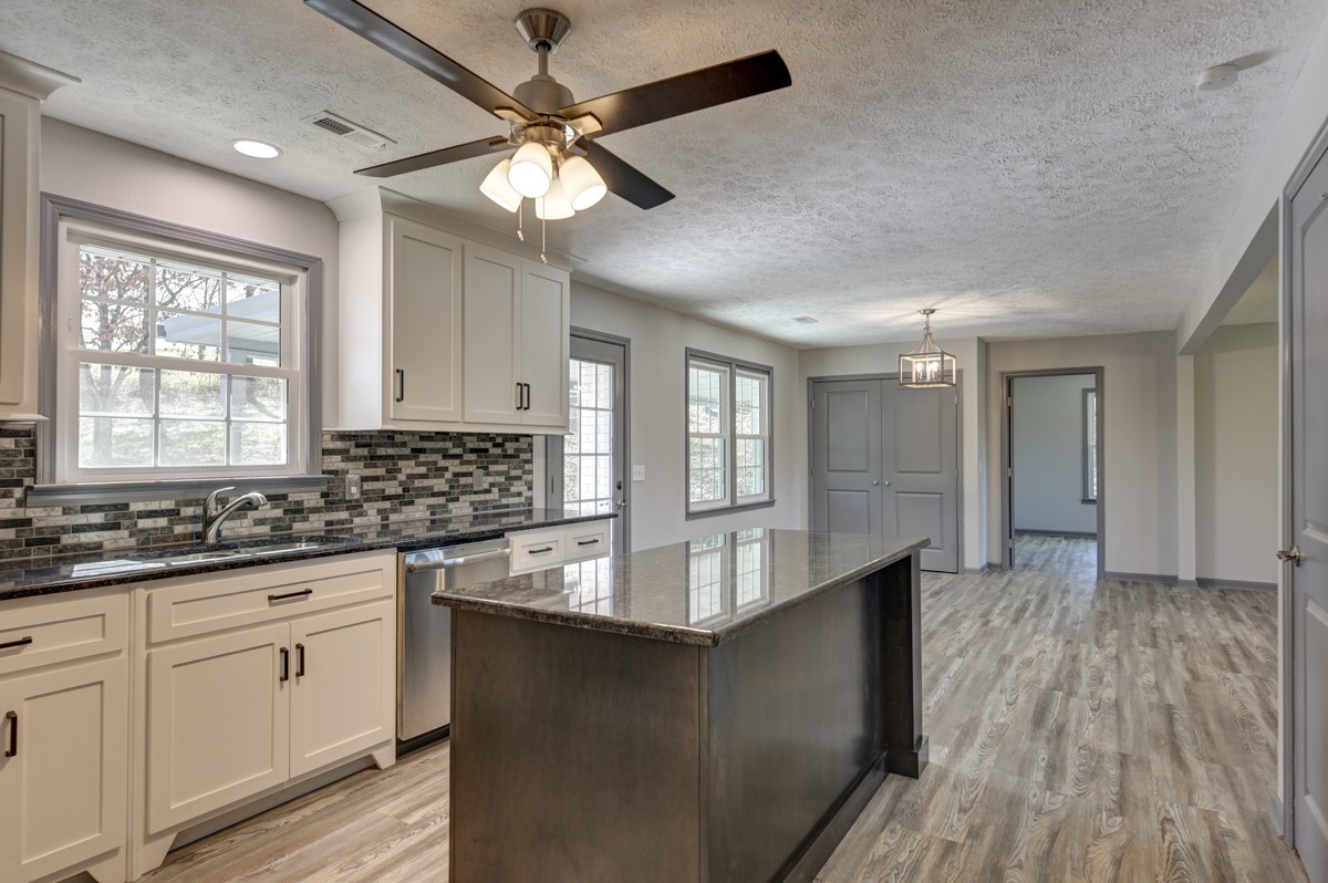 300 Garrison Branch Road Cottontown, TN 37048 - Photo 20 of 50 a kitchen with granite countertop a stove a sink and white cabinets with wooden floor