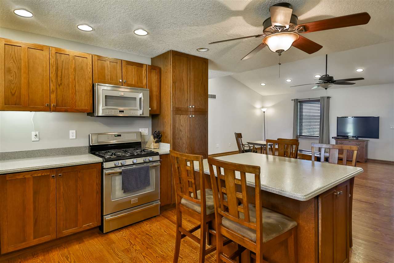5776 Daysville Road Oregon, IL 61061 - Photo 14 of 34 a kitchen with stainless steel appliances granite countertop a stove a refrigerator a microwave a sink a dining table and chairs with wooden floor