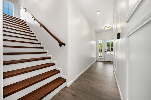a view of a livingroom with a flat screen tv wooden floor and a ceiling fan