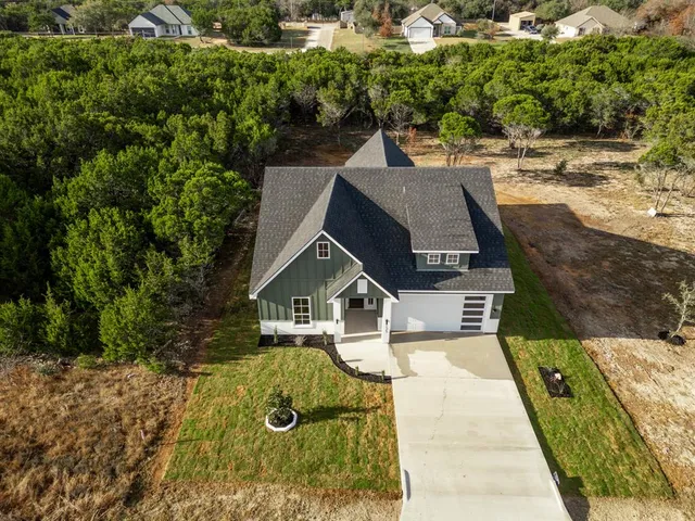 an aerial view of a house with swimming pool and large trees