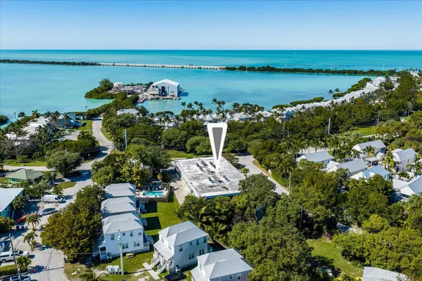 an aerial view of ocean with residential house with outdoor space and trees