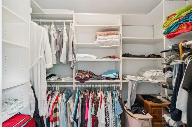 a view of walk in closet with clothes and shoes