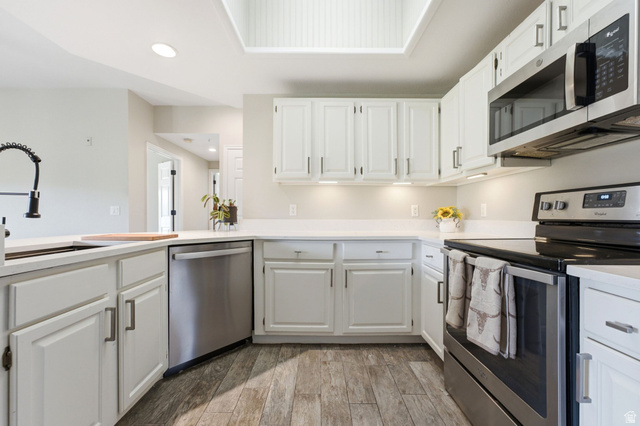 900 Bitner Road, Unit P17 Park City, UT 84098 - Photo 10 of 45 Kitchen featuring white cabinetry, light countertops, wood-finish flooring, stainless steel appliances, and a skylight with beadboard trim