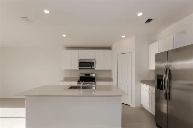 a kitchen with kitchen island stainless steel appliances a sink and a refrigerator