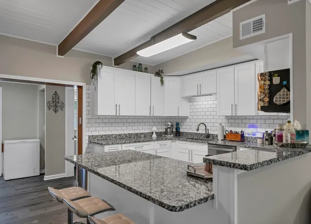 a kitchen with granite countertop a sink a stove and a wooden floor