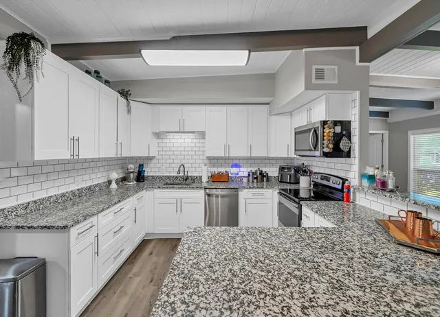 a kitchen with granite countertop lots of counter top space appliances and cabinets