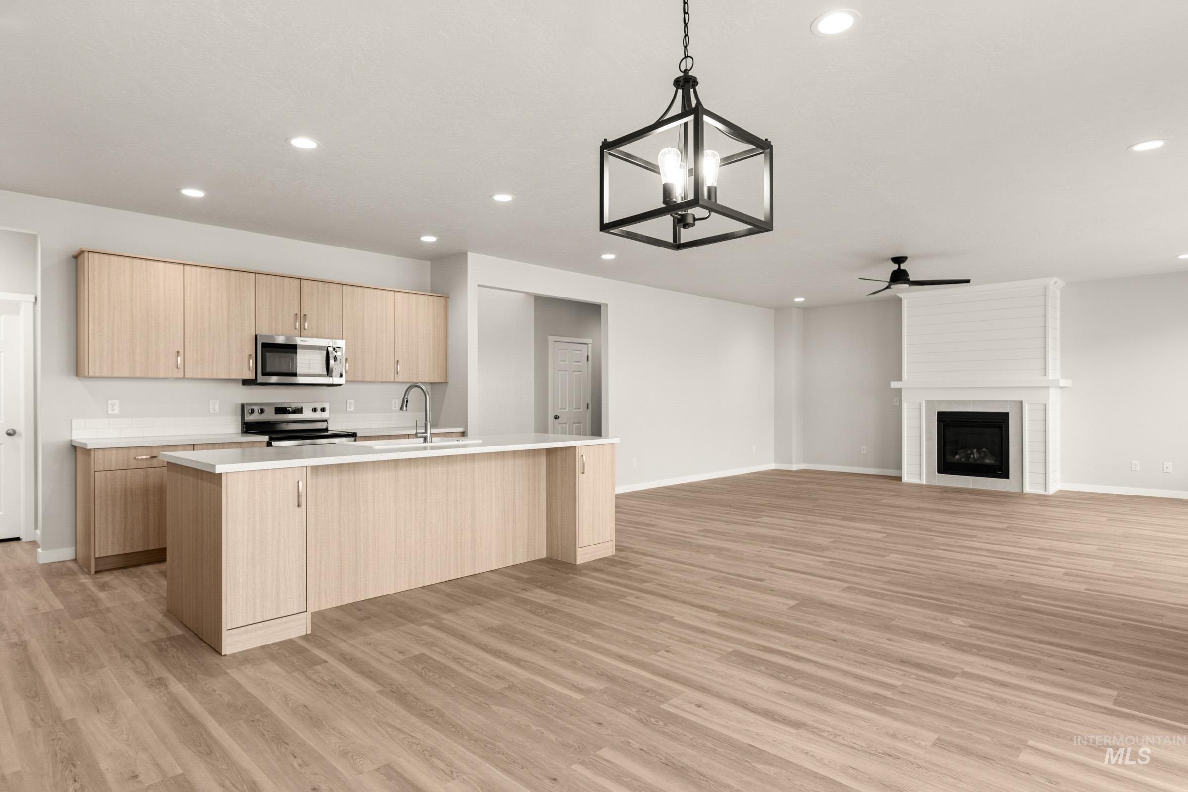 13688 Redway Court Caldwell, ID 83607 - Photo 26 of 26 Kitchen with an island with sink, suspended lighting, open floor plan, ceiling fan, and a fireplace