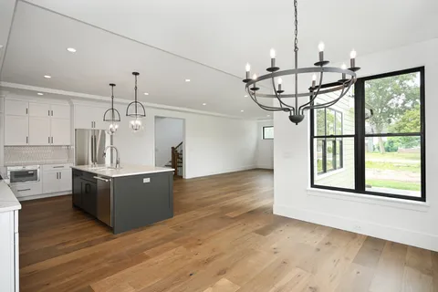 a kitchen with stainless steel appliances granite countertop a sink a window and wooden floor