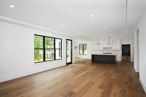 a view of an empty room with kitchen and a window