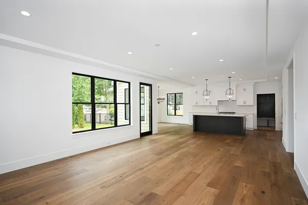 a view of an empty room with kitchen and a window