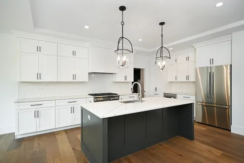 a kitchen with stainless steel appliances granite countertop a sink a stove a refrigerator and island with wooden floor