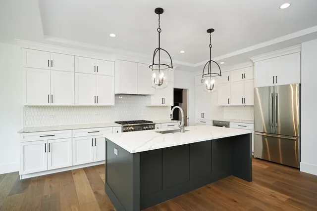 a kitchen with stainless steel appliances granite countertop a sink a stove a refrigerator and island with wooden floor