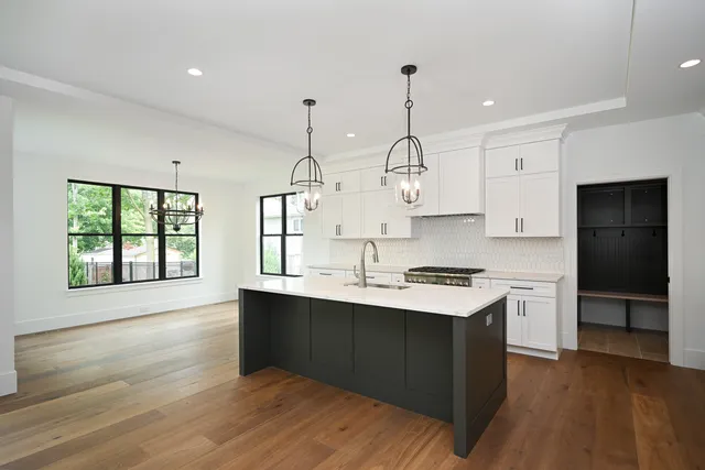 a kitchen with stainless steel appliances granite countertop a sink a stove and a wooden floors