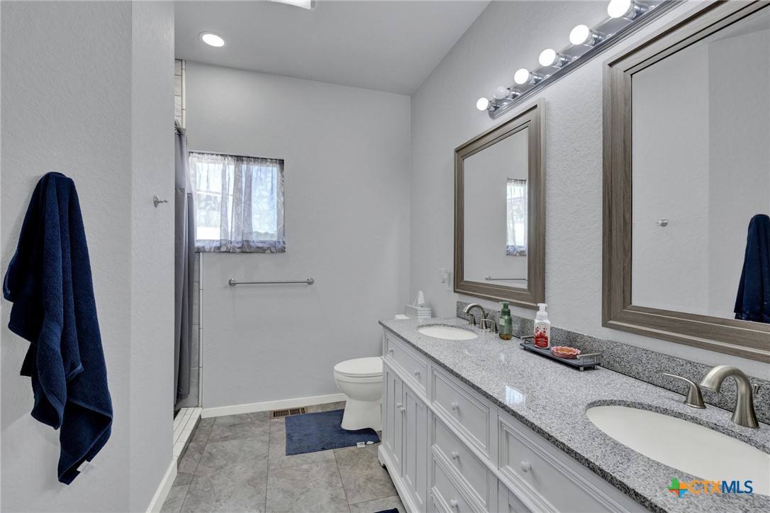 305 Lake Crest Spring Branch, TX 78070 - Photo 13 of 38 a bathroom with a double vanity sink and a mirror