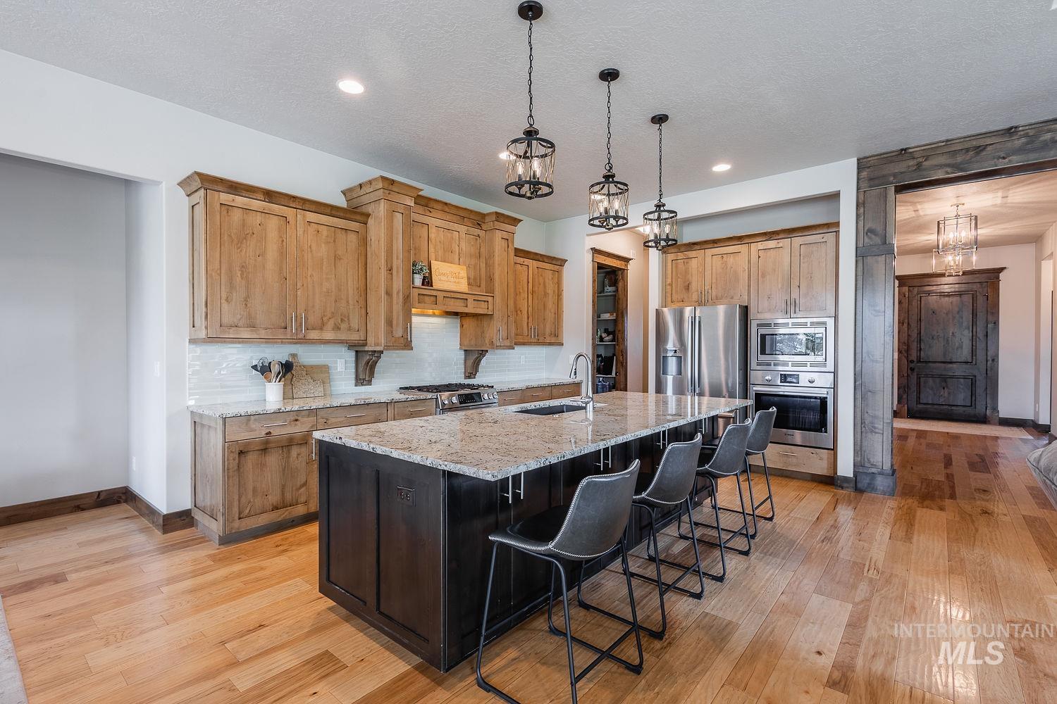 8077 Star Pass Ridge Road Nampa, ID 83686 - Photo 12 of 37 Kitchen featuring wood cabinetry, stainless steel range, and light-toned granite countertops