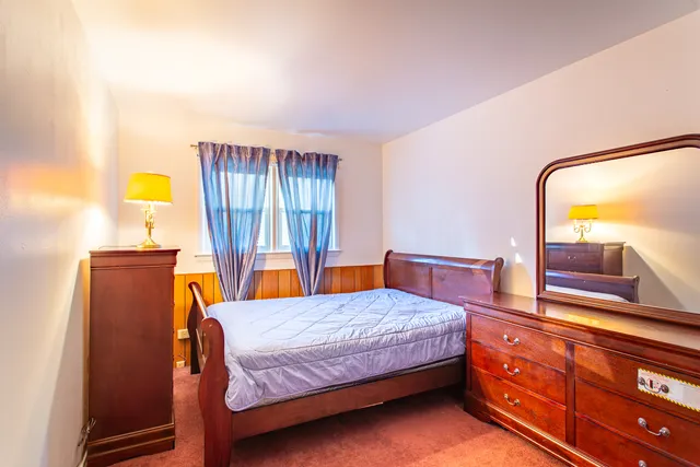 a bedroom with a bed and a dresser with mirror