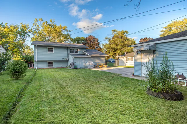 a view of house with a yard and potted plants