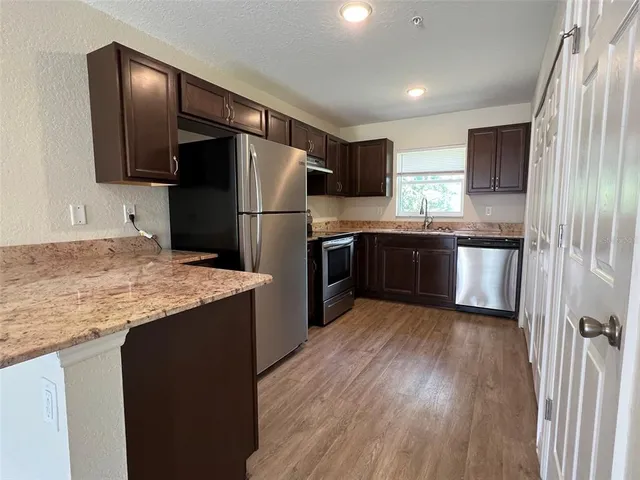 a kitchen with stainless steel appliances granite countertop a refrigerator and a stove top oven