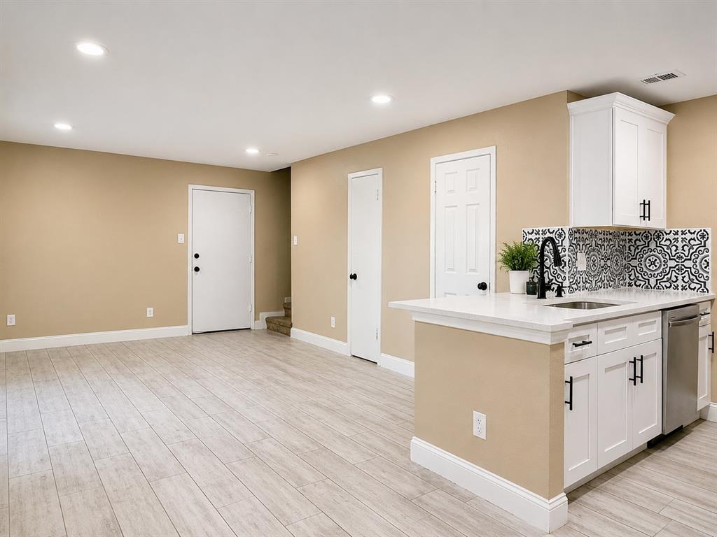 12802 Midway Road, Unit 2015 Dallas, TX 75244 - Photo 3 of 14 Light wood-finish flooring, recessed lighting, white cabinetry with black hardware, white countertop, and a patterned tile backsplash