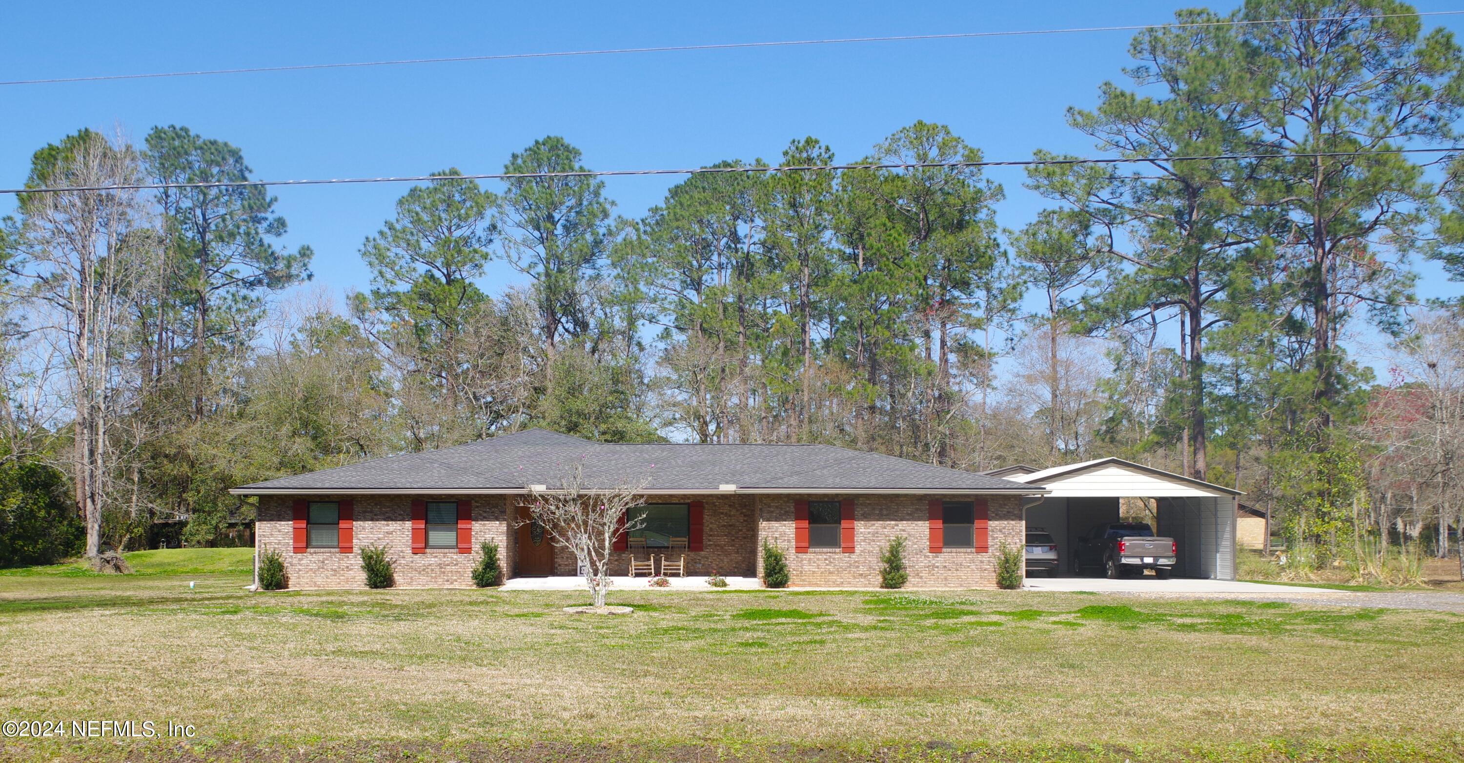 54065 Howard Road Callahan, FL 32011 - Photo 2 of 69 a view of a white house with a big yard and large trees
