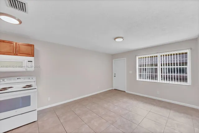 a view of an empty room with a kitchen and a stove top oven