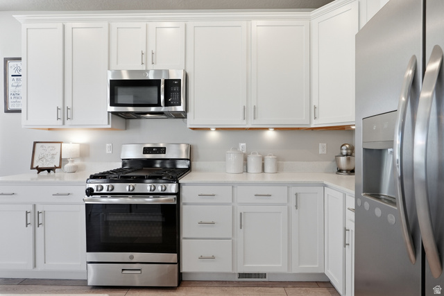 3244 West 1670th Street North Provo, UT 84601 - Photo 18 of 56 Kitchen featuring white shaker cabinetry with crown molding, stainless steel appliances, light-toned countertops, and recessed under-cabinet lighting