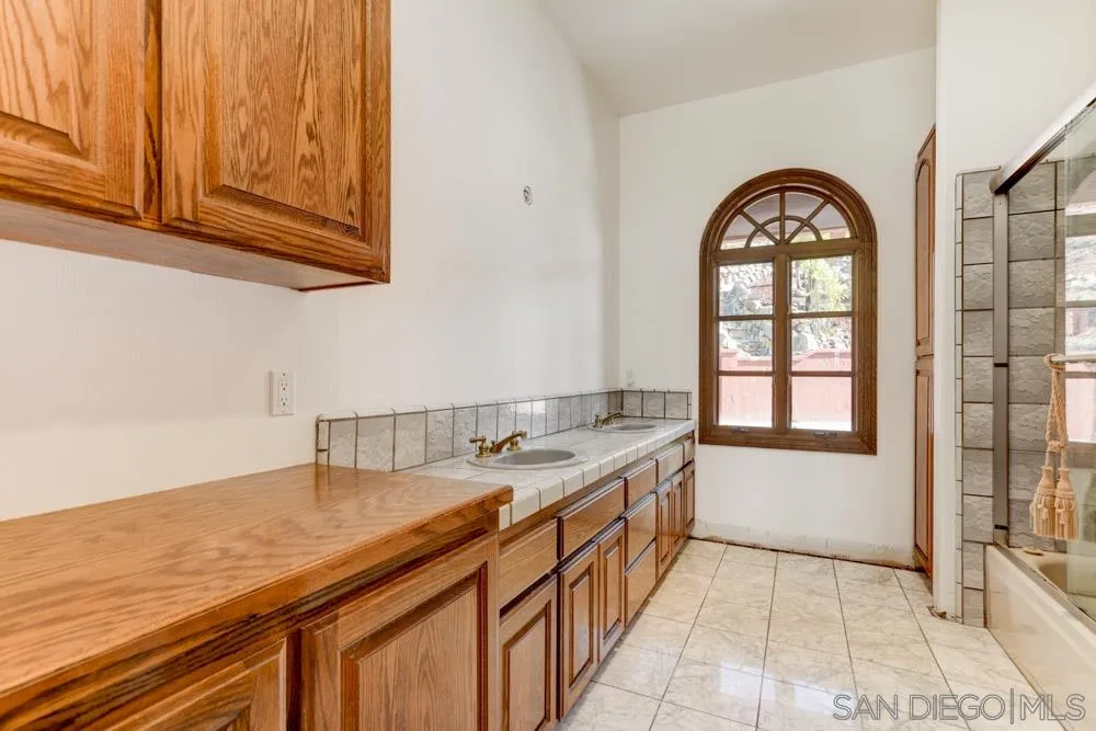 1762 Kings Road Vista, CA 92084 - Photo 21 of 24 a bathroom with a granite countertop sink a mirror and a bathtub