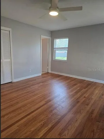 a view of an empty room with wooden floor and a window