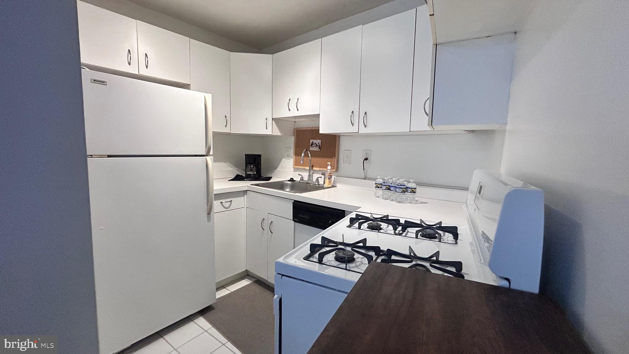 1239 Vermont Avenue Northwest, Unit 204 Washington, DC 20005 - Photo 11 of 39 a kitchen with a refrigerator a stove a sink and white cabinets