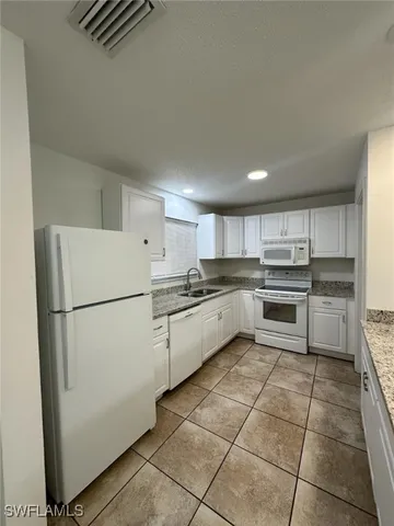 a kitchen with a refrigerator and white cabinets