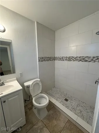 a bathroom with a granite countertop sink a toilet a mirror and shower