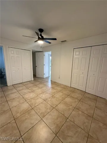 a view of an empty room and chandelier fan