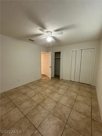 a view of an empty room and chandelier fan
