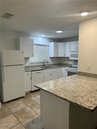 a kitchen with granite countertop cabinets and refrigerator