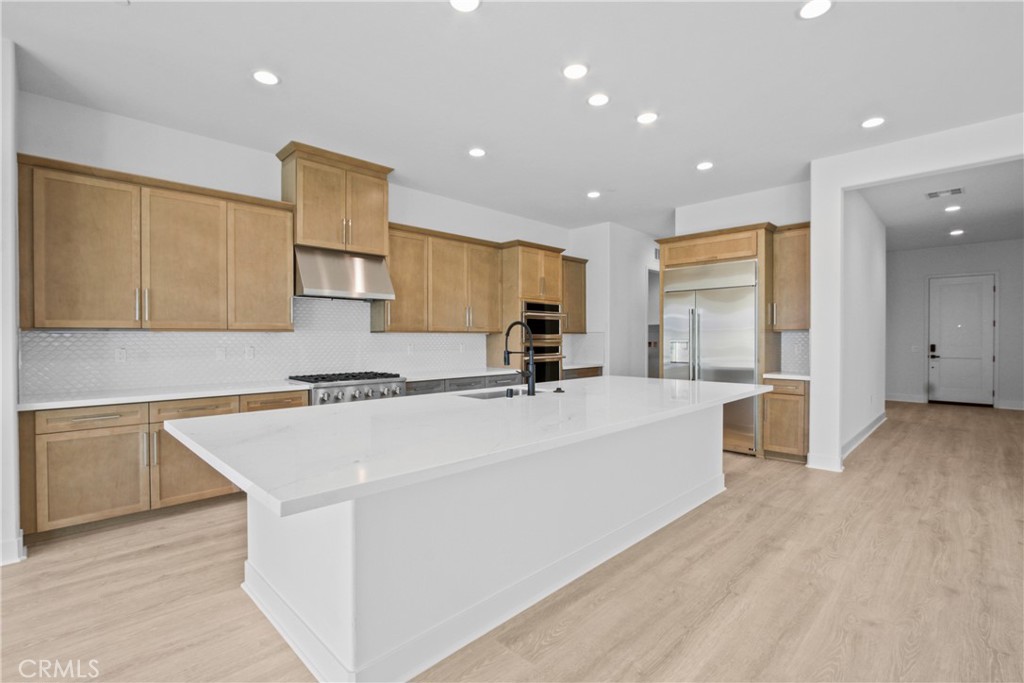 4685 Avondale Court Chino, CA 91710 - Photo 4 of 16 a large white kitchen with kitchen island a stove a sink a refrigerator and white cabinets with wooden floor