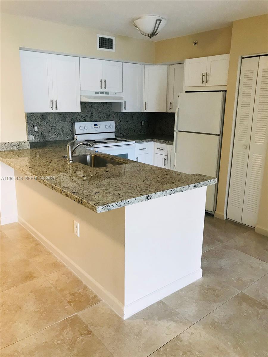 2031 Renaissance Boulevard, Unit 106 Miramar, FL 33025 - Photo 17 of 19 a kitchen with stainless steel appliances granite countertop a sink a stove a refrigerator a white stove and white cabinets