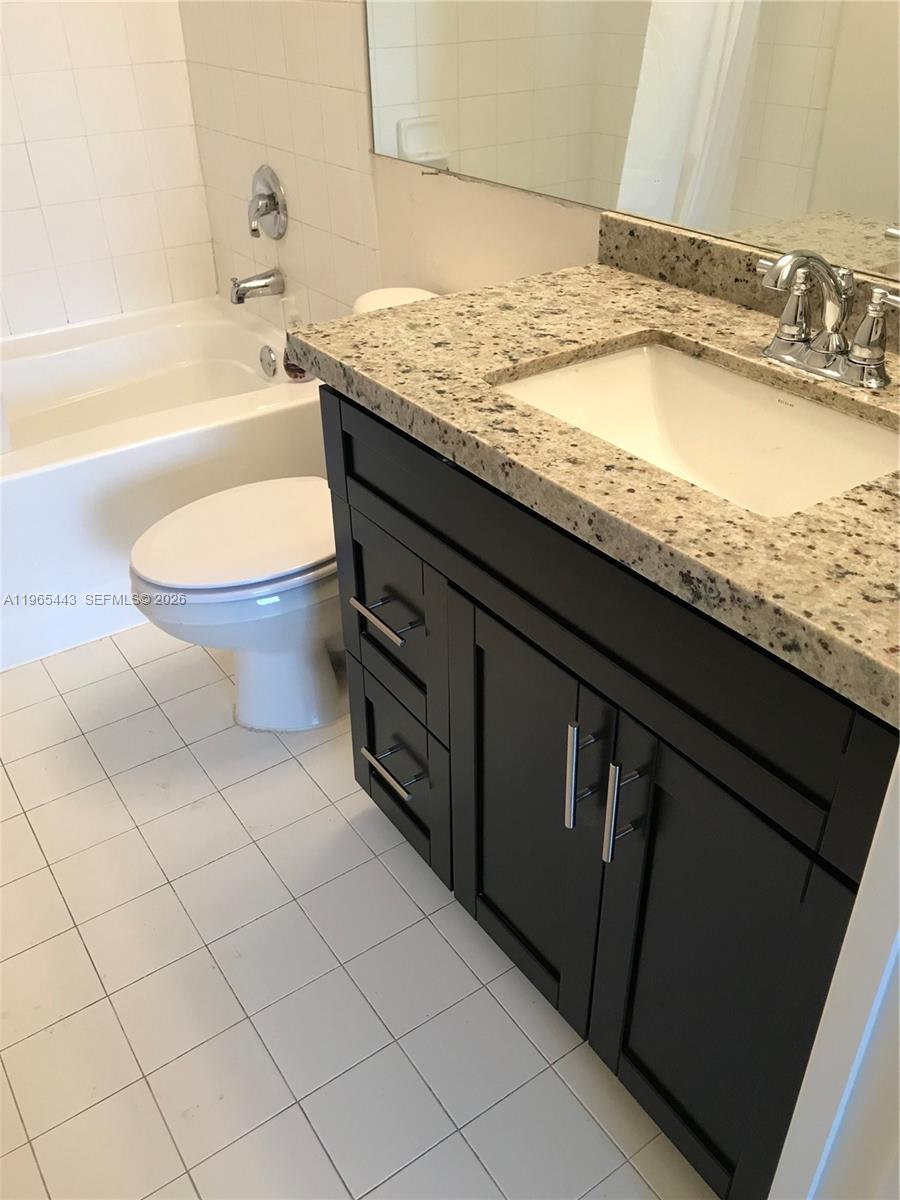 2031 Renaissance Boulevard, Unit 106 Miramar, FL 33025 - Photo 18 of 19 a bathroom with a granite countertop sink toilet and bathtub