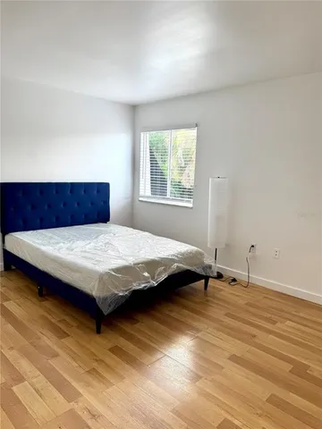 a bedroom with a bed and wooden floor