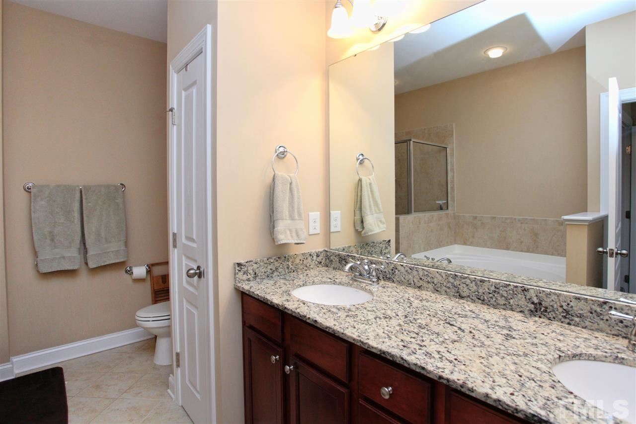 618 Democracy Street Raleigh, NC 27603 - Photo 16 of 24 a bathroom with a granite countertop sink a toilet and shower